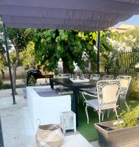 a patio with a table and chairs under an umbrella at Detached renovated cottage with a garden 3 min walk from the beach in Vrahati