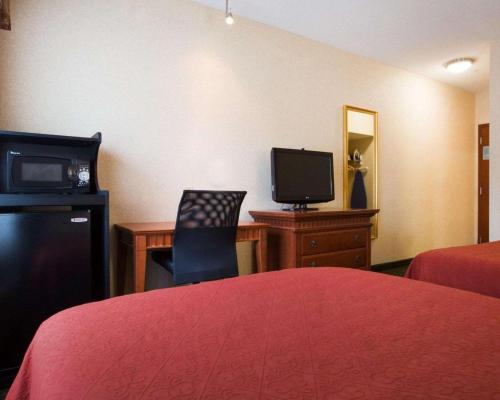 a hotel room with a bed and a desk with a television at Econo Lodge Glens Falls - Lake George in Glens Falls