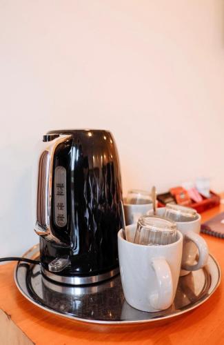 a coffee maker on a tray with cups on a table at The Grand Hotel & Bar - Akaroa in Akaroa