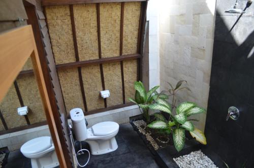 a bathroom with a toilet and some plants at Unzipp Lumbung Gili Trawangan in Gili Trawangan
