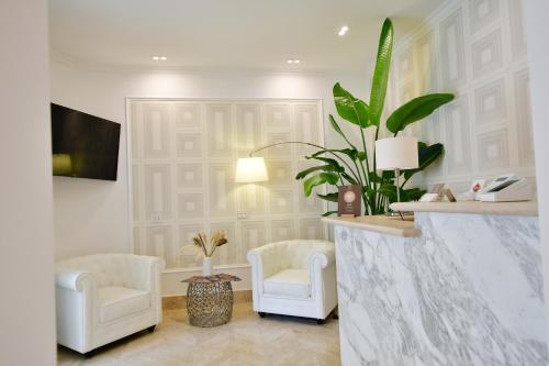 a living room with two white chairs and a plant at Domus De Cinti Boutique Rooms in Tivoli