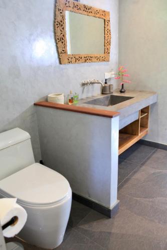 a bathroom with a sink and a toilet and a mirror at House of Rising Sun in Thong Nai Pan Noi