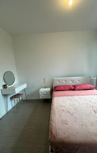 une chambre avec un lit, une table et un miroir dans l'établissement Home in Paris, à Bezons