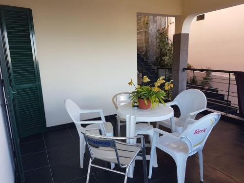 einen weißen Tisch und Stühle mit Topfpflanze auf dem Balkon in der Unterkunft Madeira house garden Villa in Estreito de Câmara de Lobos
