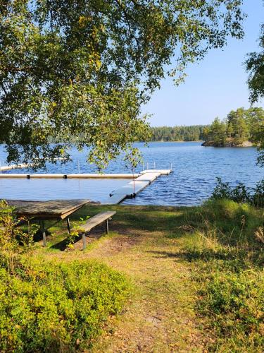 a bench sitting next to a lake with a dock at Stuga Ani in Svartå