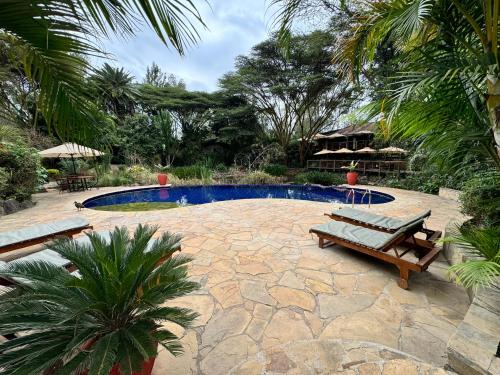 a patio with two benches and a swimming pool at Wildebeest Eco Camp in Nairobi