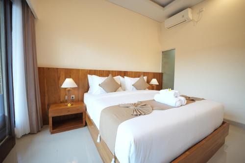 a bedroom with a large white bed and a window at Winaka Ubud in Ubud