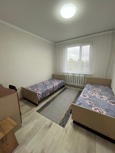 a room with two beds and a window at Трёхкомнатная квартира в центре Борового in Borovoye