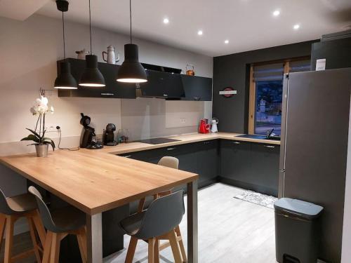 une cuisine avec une table en bois et quelques armoires noires dans l'établissement Maison 120 m2 à Gerardmer proche centre ville, à Gérardmer