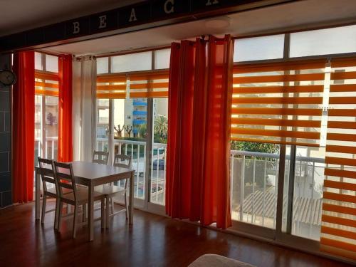 ein Esszimmer mit roten Vorhängen sowie einem Tisch und Stühlen in der Unterkunft Apartamento Playa Gandía in Playa de Gandia
