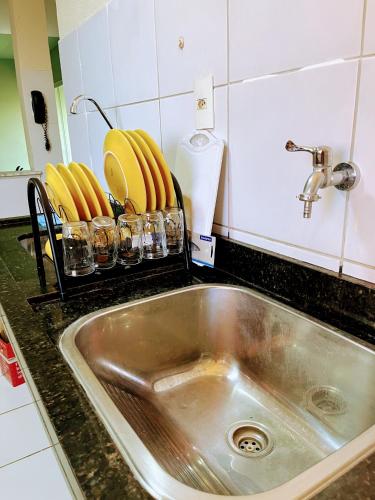 a kitchen sink with plates and glasses on a counter at Impera House 2 km do centro in Imperatriz