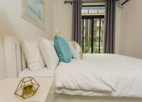 a bedroom with a white bed with pillows and a window at Accra Luxury Apartments at Embassy Gardens in Accra