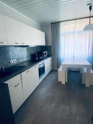a kitchen with white cabinets and a white table at 1923 Wohnung by Gerda in Etgersleben