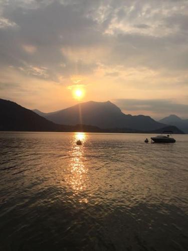 a sunset on a lake with a boat in the water at In center Cà del Pescatore lake view in Lierna