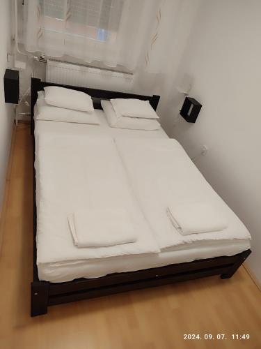 a bed in a room with white sheets and pillows at LBB apartman in Sátoraljaújhely
