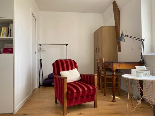 un salon avec une chaise rouge et une table dans l'établissement Charmant perchoir plein sud à Boulogne !, à Boulogne-Billancourt