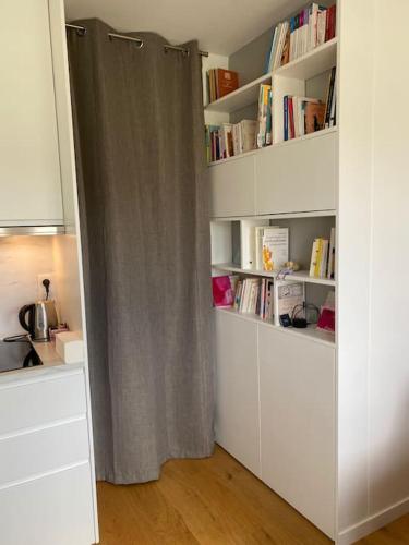une pièce avec une étagère à livres avec un rideau dans l'établissement Charmant perchoir plein sud à Boulogne !, à Boulogne-Billancourt
