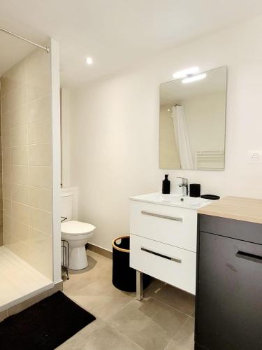 une salle de bain avec un lavabo, des toilettes et un miroir dans l'établissement Maison bord de mer, à Varaville
