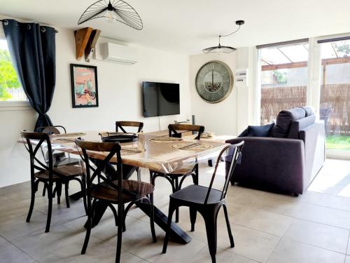 un salon avec une table, des chaises et un canapé dans l'établissement Maison bord de mer, à Varaville