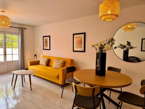 a living room with a yellow couch and a table at Falesia Gardens in Caniço