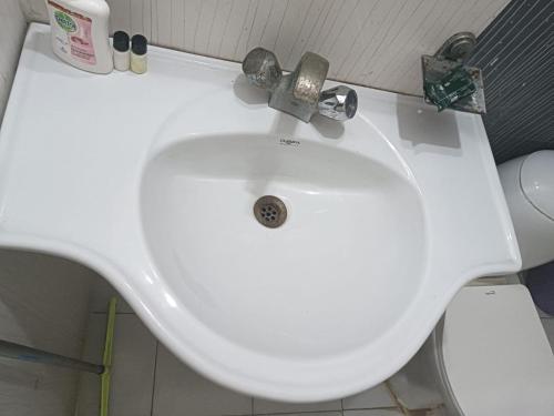 a white sink in a bathroom with a toilet at VisitorStayInn in Vrindāvan
