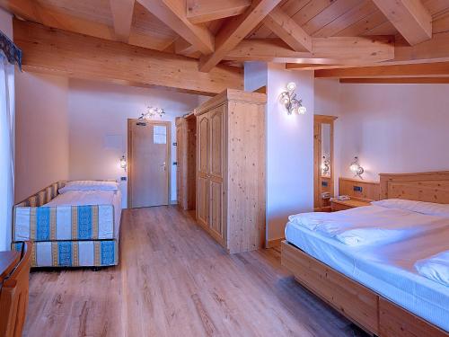 two beds in a room with wooden ceilings at Hotel Madonna delle Nevi in Folgarida