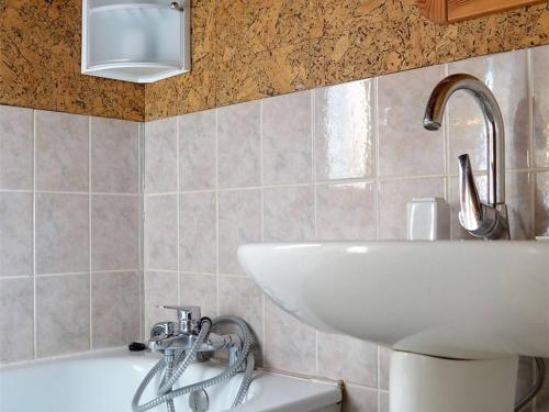 La salle de bains est pourvue d'un lavabo, d'une baignoire et d'un lavabo blanc. dans l'établissement Chalet individuel pied de pistes avec WiFi - FR-1-593-59, aux Angles