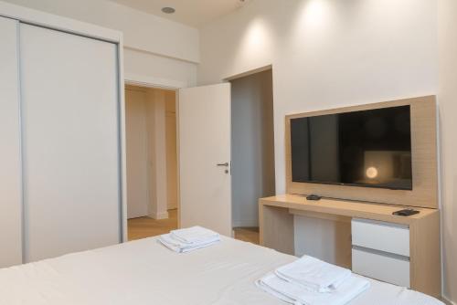 a white bedroom with a tv and a bed at Apartmani Zepterme by CENTRAL in Vrnjačka Banja