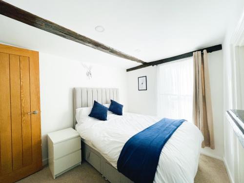 a bedroom with a bed with blue pillows and a window at Chelmsford City - 17th Century Apartment in Chelmsford