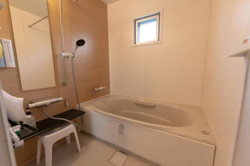 a bathroom with a bath tub and a window at Villa Blue Terasu 宮古島 in Matsubara