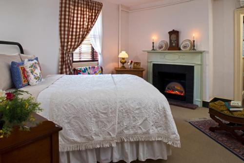 a bedroom with a white bed and a fireplace at Rachael's Dowry Bed and Breakfast in Baltimore