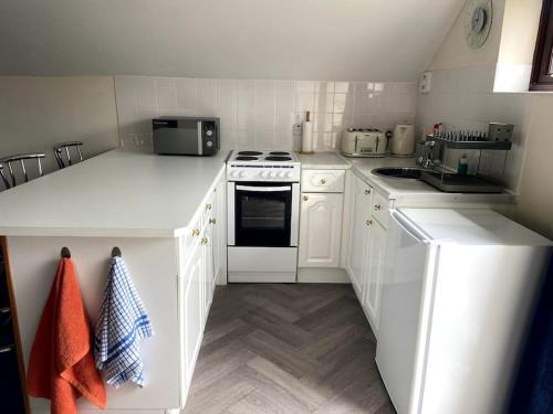 a white kitchen with white cabinets and appliances at The Bedsit in Pembrokeshire