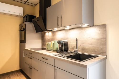 a kitchen with white cabinets and a sink at Apart Hotel Lang in Altenahr