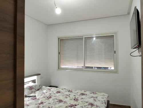 a bedroom with a bed and a window at Résidence les deux palmiers Temara Rabat in Temara