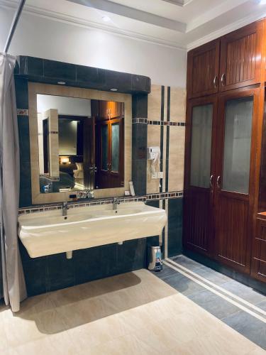 a bathroom with a large sink and a large mirror at Sunset BnB Creek in Karachi