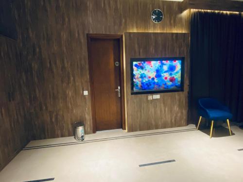 a room with a blue chair and a tv on a wall at Sunset BnB Creek in Karachi