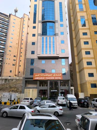 a parking lot with cars parked in front of a building at Jawharat dakher hotel فندق جوهرة ذاخر توصيل مجاني من و إلى الحرم in Makkah