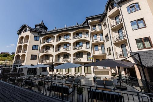a large building with tables and umbrellas in front of it at Premium hotel & SPA in Bukovel