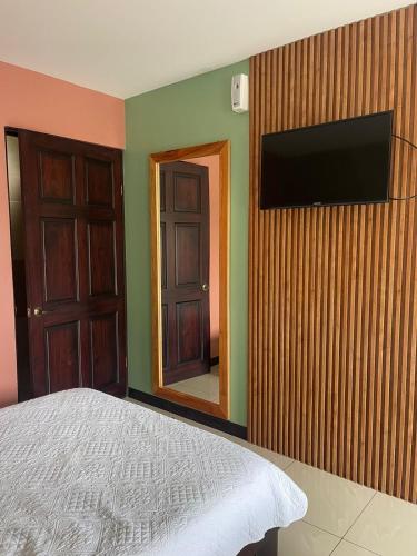 a bedroom with a bed and a television on a wall at Hotel Mi Linda Tierra in Quesada