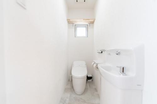a white bathroom with a toilet and a sink at Villa Blue Terasu 宮古島 in Matsubara