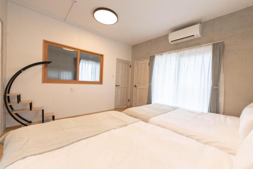 a bedroom with two beds and a window at Villa Blue Terasu 宮古島 in Matsubara