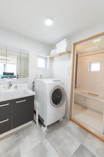 a bathroom with a washing machine and a sink at Villa Blue Terasu 宮古島 in Matsubara