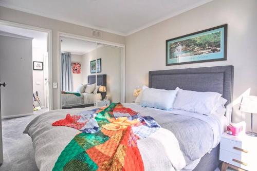 a bedroom with a bed with a colorful blanket on it at 1BR eco apartment with tennis court and carpark in Melbourne