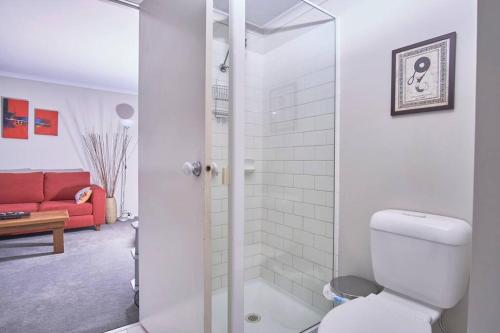 a bathroom with a toilet and a red couch at 1BR eco apartment with tennis court and carpark in Melbourne