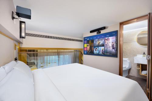 a bedroom with a large white bed and a bathroom at Jingli Hotel - Beijing New National Exhibition Capital Airport in Houshayu
