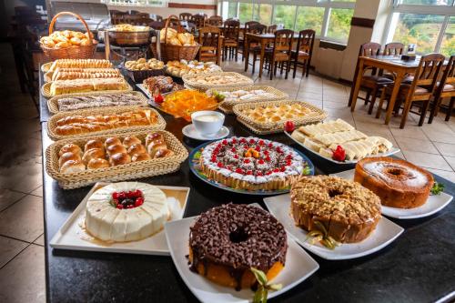 a table filled with different types of cakes and pastries at Hotel Leão da Montanha in Campos do Jordão