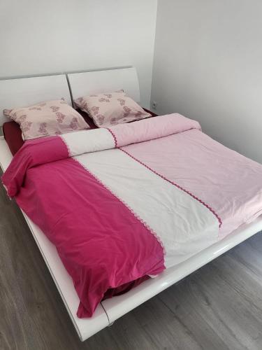 - un lit blanc avec des draps et des oreillers roses et blancs dans l'établissement Rumilly, Appartement T3 récent proche Annecy et Aix-les-bains, à Bloye