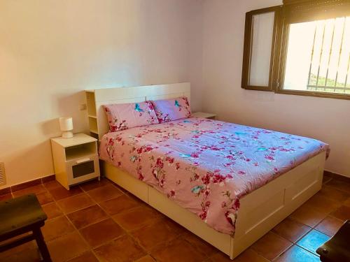 une chambre avec un lit avec une couette rose et une fenêtre dans l'établissement Casa Rural Camino de la Fuente, à Teroleja