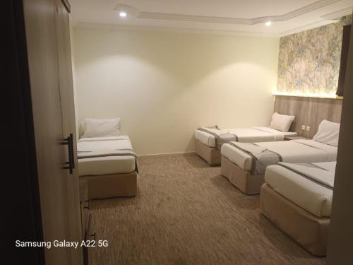 a hotel room with three beds and a window at فندق الخلفاء الفيصلية in Makkah