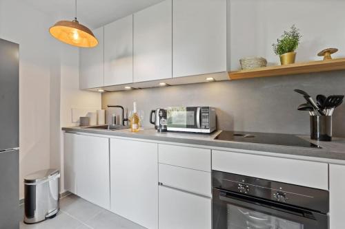 a kitchen with white cabinets and a microwave at 3 Zimmer EG Wohnung direkt am Kurpark in Bad Aibling